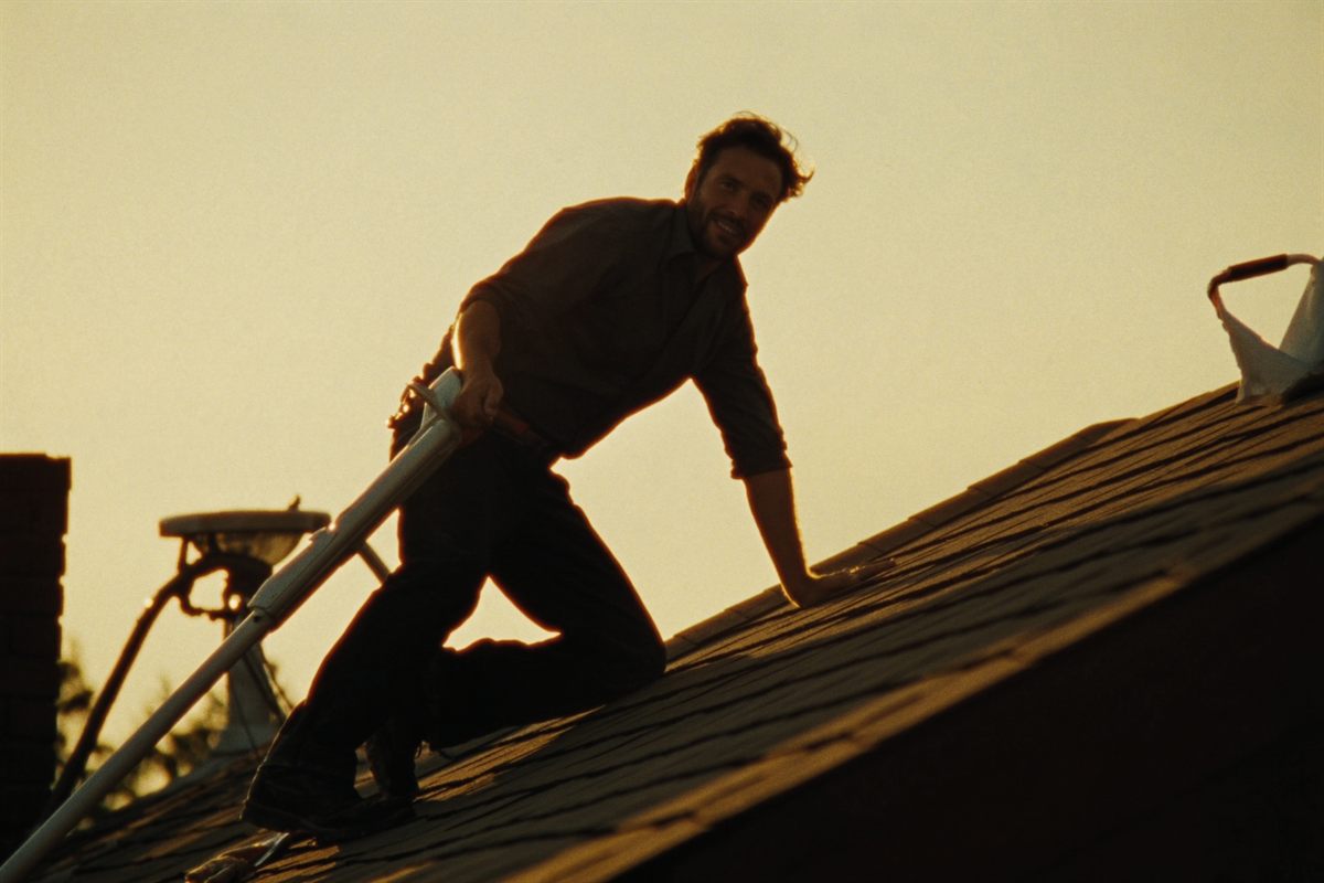 A roofer working on a residential roof at golden hour