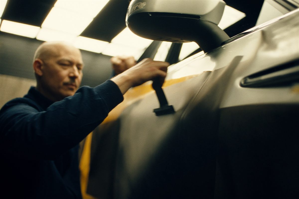 An installer squeegeeing vinyl wrap film onto a car panel